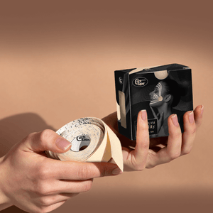 Person holding a roll of face tape with a box labeled Cure Tape against a beige background