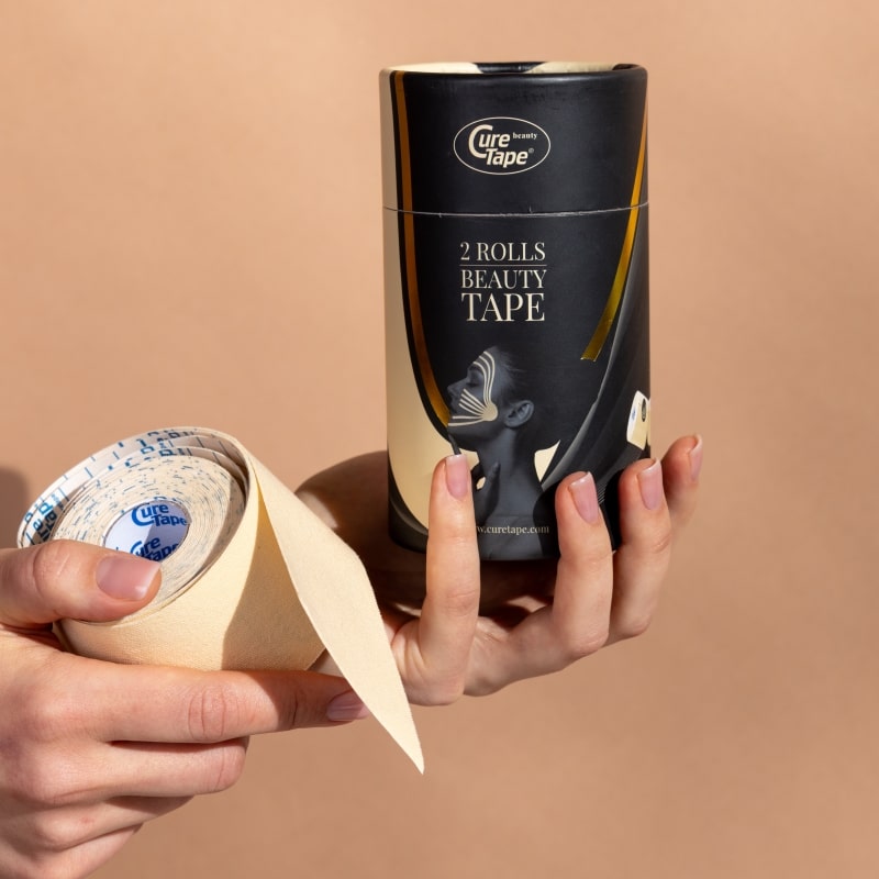 Two rolls of CureTape Beauty 5 cm tape roll for non-invasive face lifting and wrinkle reduction on a beige background