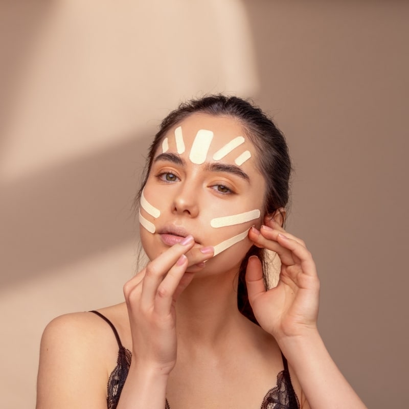 Woman applying korean face tape on her forehead and cheeks