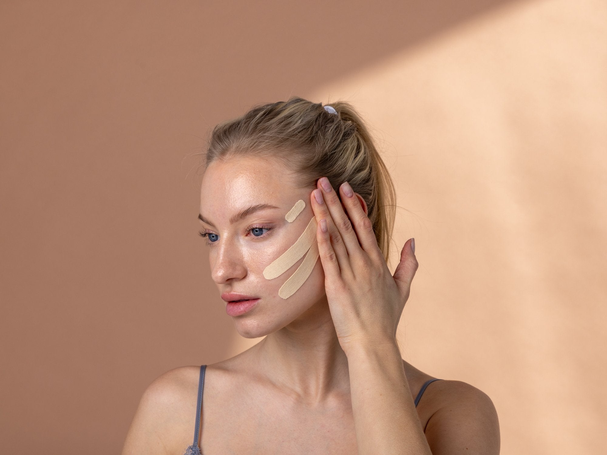 Model applying BeautyTape facial tape for natural wrinkle care and face lifting