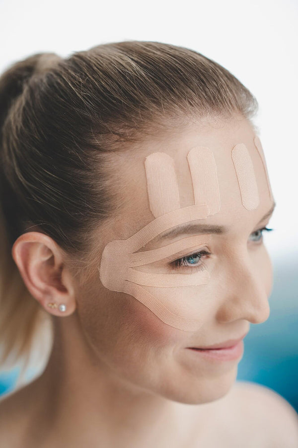 woman with a face tape on her forehead and eye area to reduce wrinkles