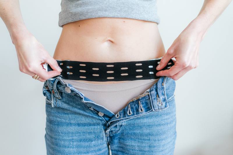 Model applying CureTape Punch for abdominal pain during menstruation