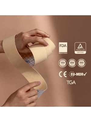 Hand holding a roll of medical face tape with certification logos on a beige background