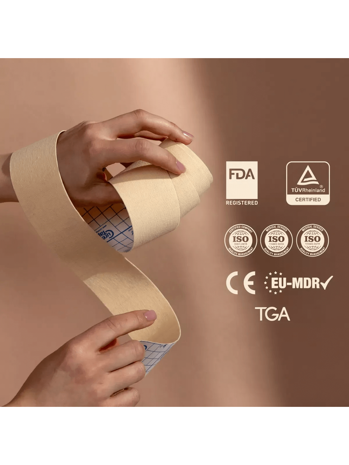 Hand holding a roll of medical face tape with certification logos on a beige background