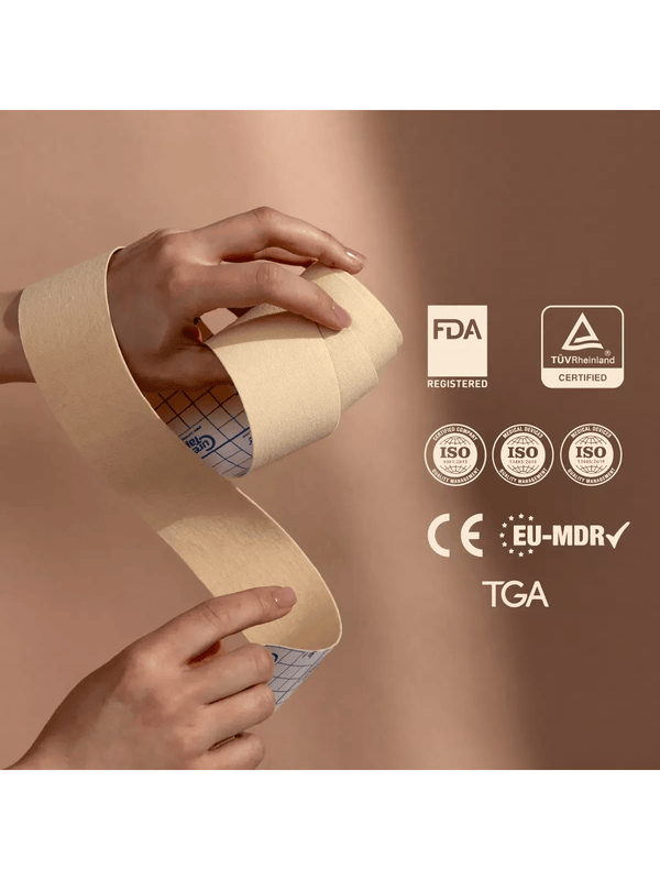 Hand holding a roll of medical face tape with certification logos on a beige background